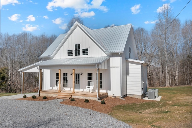 modern farmhouse featuring metal roof, a porch, central air condition unit, board and batten siding, and gravel driveway