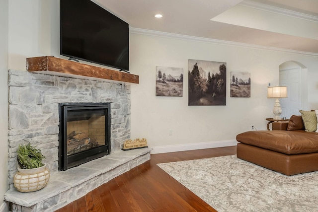 living room featuring crown molding, recessed lighting, dark wood-type flooring, a stone fireplace, and baseboards