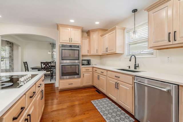 kitchen with light wood-style flooring, appliances with stainless steel finishes, hanging light fixtures, light countertops, and a sink