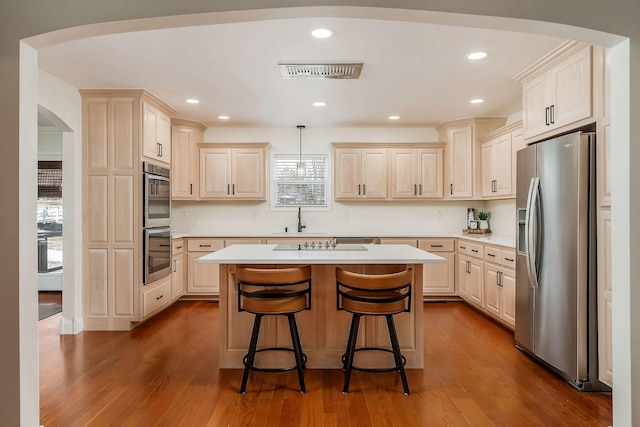 kitchen featuring stainless steel appliances, hanging light fixtures, a kitchen island, and light countertops