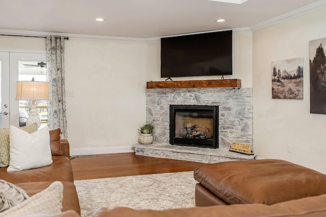 living room featuring a fireplace, crown molding, recessed lighting, wood finished floors, and baseboards