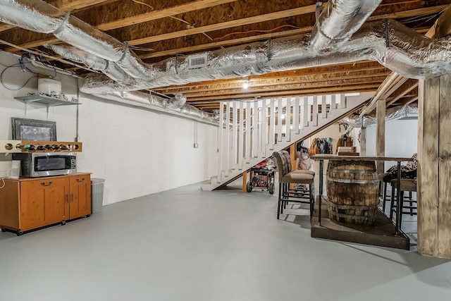 unfinished basement featuring visible vents and stairs