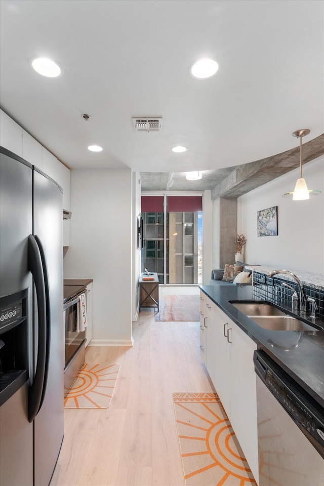 kitchen with stainless steel appliances, a sink, visible vents, white cabinetry, and dark countertops