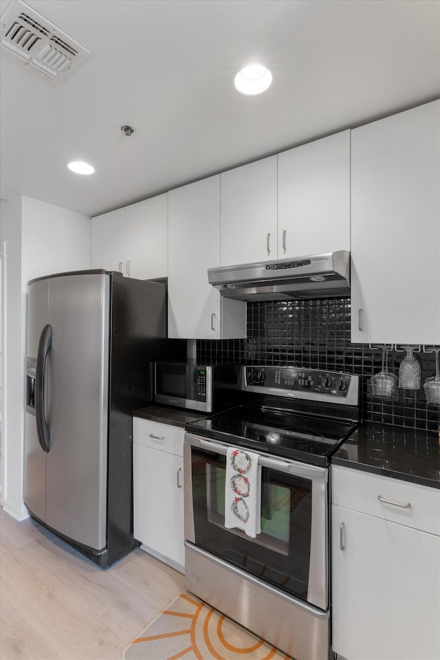 kitchen featuring visible vents, white cabinets, dark countertops, appliances with stainless steel finishes, and under cabinet range hood