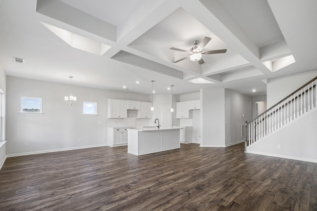 unfurnished living room with baseboards, coffered ceiling, dark wood-type flooring, and ceiling fan with notable chandelier