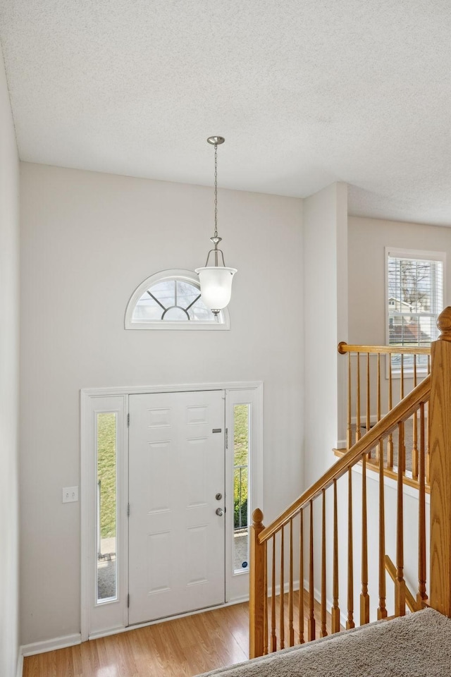 entryway with a textured ceiling, baseboards, and light wood-style floors