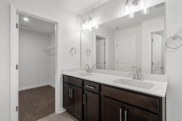 full bathroom with a spacious closet, double vanity, a sink, and visible vents