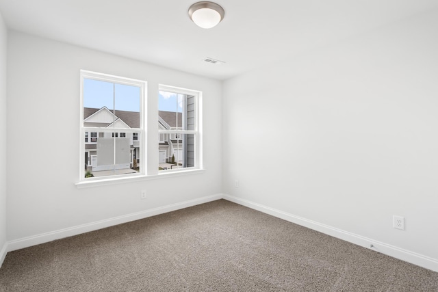 spare room featuring carpet floors, visible vents, and baseboards