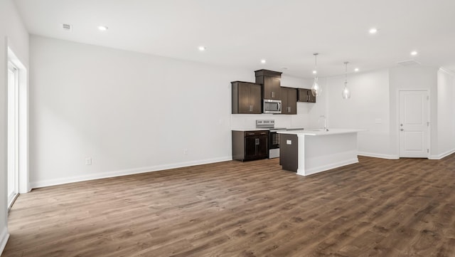 kitchen featuring dark wood-style floors, a center island with sink, light countertops, appliances with stainless steel finishes, and open floor plan