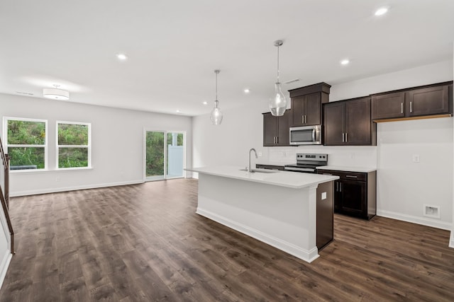 kitchen featuring stainless steel appliances, dark brown cabinets, light countertops, pendant lighting, and a sink