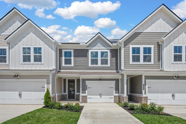 townhome / multi-family property with driveway, stone siding, an attached garage, and board and batten siding