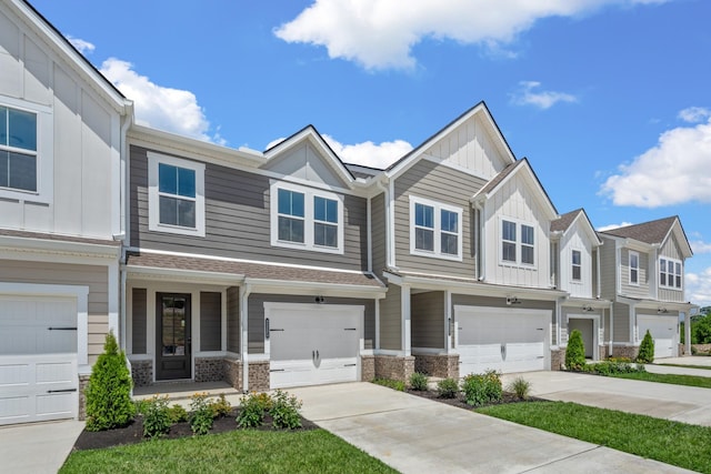 townhome / multi-family property with a garage, concrete driveway, board and batten siding, and stone siding