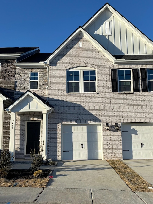 view of front of property with a garage, concrete driveway, brick siding, and board and batten siding