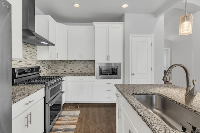 kitchen featuring stainless steel appliances, white cabinetry, a sink, and wall chimney exhaust hood