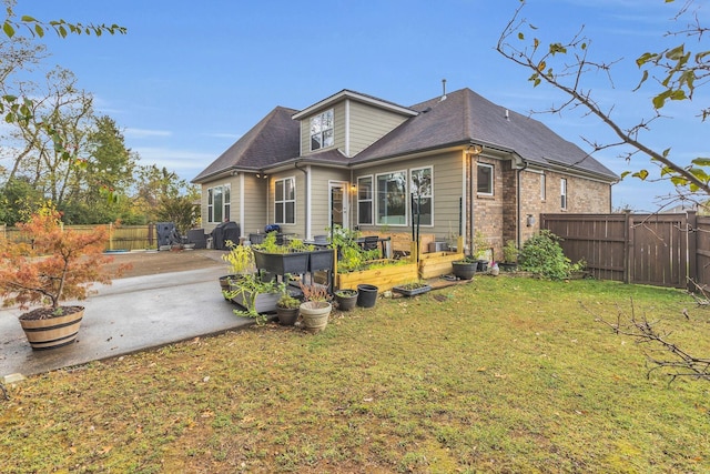 rear view of property with a yard, brick siding, a patio, and fence