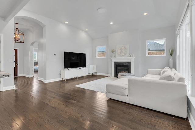 living area featuring recessed lighting, a notable chandelier, dark wood-style flooring, baseboards, and a glass covered fireplace