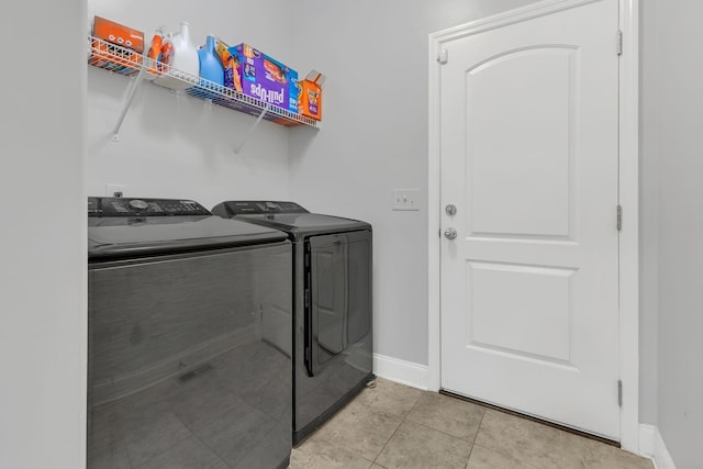 washroom with laundry area, light tile patterned floors, baseboards, and washer and clothes dryer