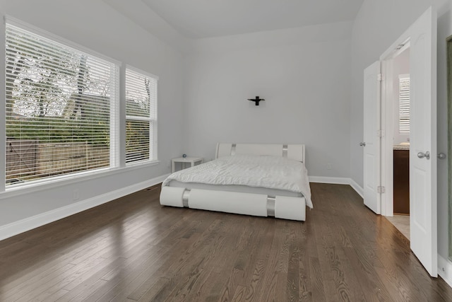 bedroom featuring multiple windows, baseboards, and dark wood-type flooring