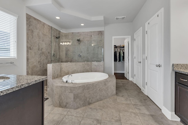 bathroom with vanity, visible vents, a bath, a walk in closet, and walk in shower