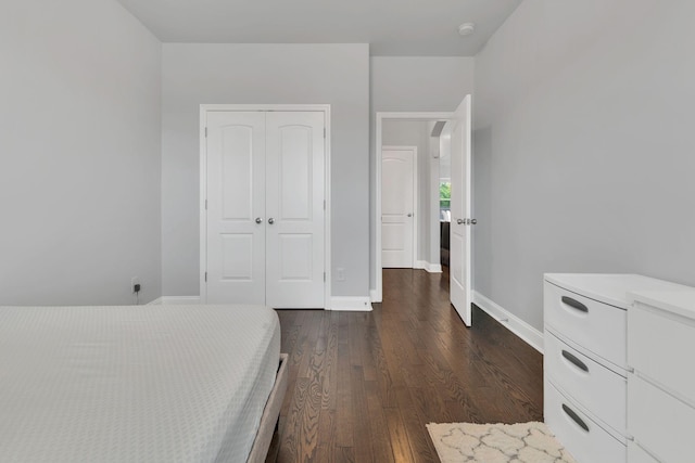 bedroom with dark wood-type flooring, a closet, and baseboards