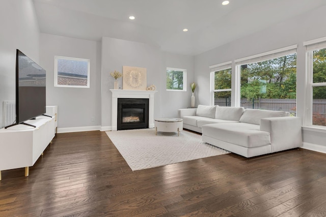 unfurnished living room with baseboards, dark wood-style flooring, a glass covered fireplace, and recessed lighting