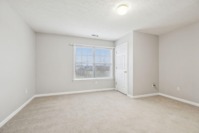 carpeted spare room featuring visible vents, baseboards, and a textured ceiling