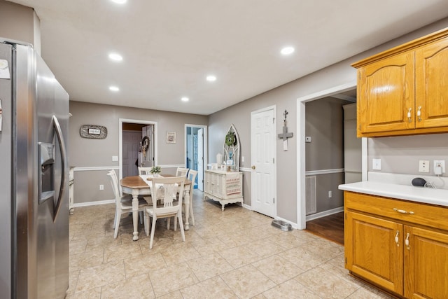 kitchen featuring baseboards, stainless steel fridge with ice dispenser, brown cabinets, light countertops, and recessed lighting