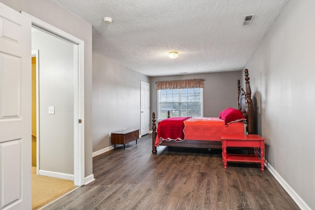 bedroom featuring a textured ceiling, baseboards, and wood finished floors