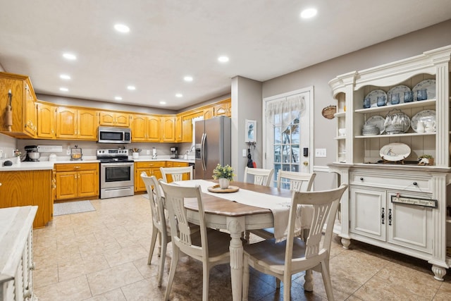 kitchen featuring recessed lighting, a sink, light countertops, appliances with stainless steel finishes, and brown cabinets