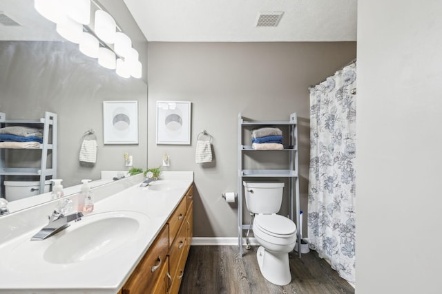 bathroom with toilet, visible vents, a sink, and wood finished floors