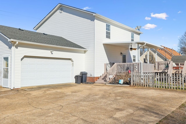 view of property exterior featuring a garage, driveway, a shingled roof, and a ceiling fan