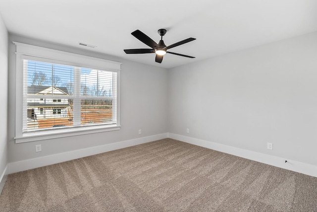 carpeted empty room with baseboards, visible vents, and a ceiling fan