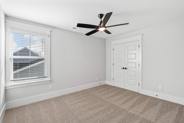 unfurnished bedroom featuring a closet, visible vents, a ceiling fan, carpet flooring, and baseboards