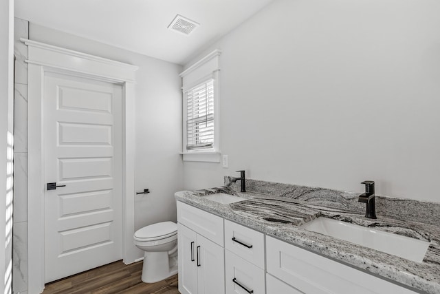 bathroom with wood finished floors, visible vents, a sink, and double vanity