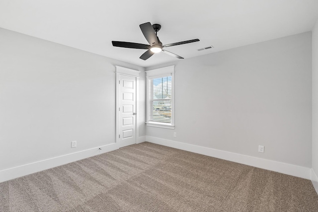 carpeted spare room featuring visible vents, ceiling fan, and baseboards