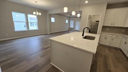 kitchen with light countertops, a sink, a center island with sink, and white cabinetry