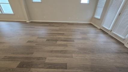 unfurnished room with dark wood finished floors and baseboards