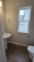 bathroom with wood finished floors, toilet, and baseboards