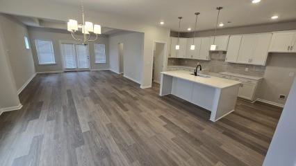 kitchen featuring a kitchen island with sink, light countertops, hanging light fixtures, and white cabinetry