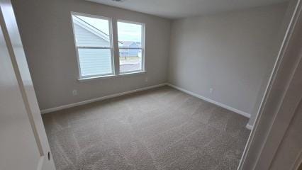 carpeted empty room featuring baseboards