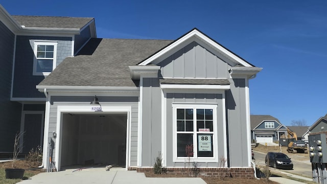 exterior space with board and batten siding, a shingled roof, and an attached garage