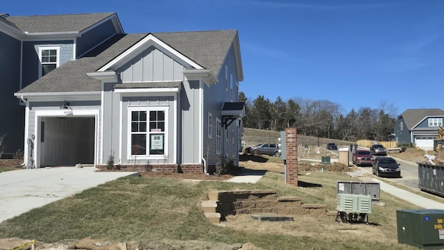 view of front facade with roof with shingles, an attached garage, board and batten siding, driveway, and a front lawn