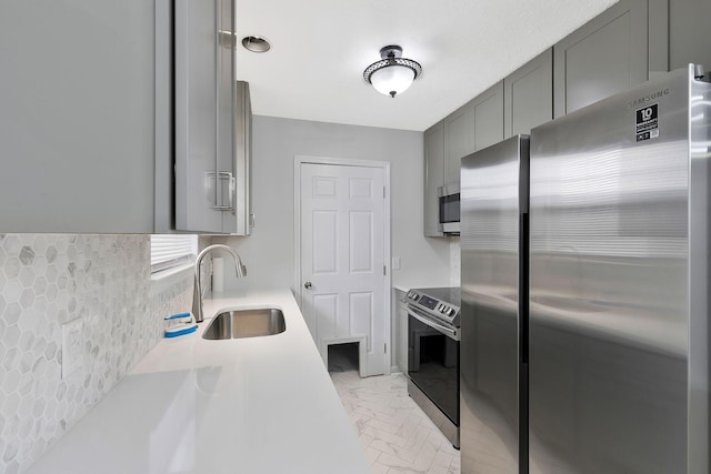 kitchen featuring appliances with stainless steel finishes, gray cabinets, a sink, and light countertops