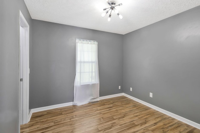 empty room with visible vents, baseboards, light wood-style flooring, and a textured ceiling