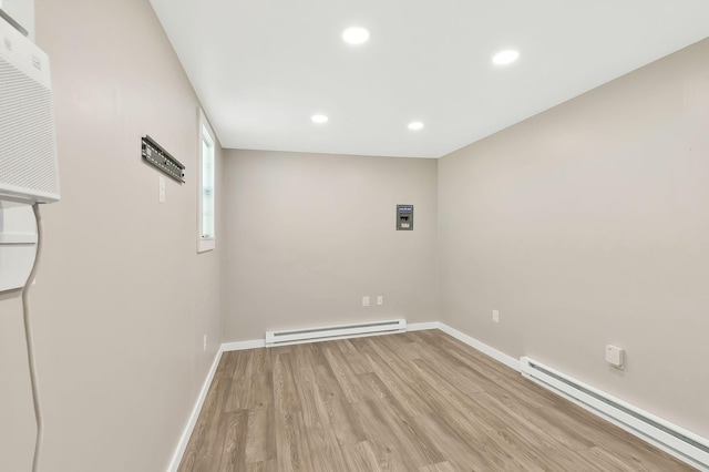 spare room with a baseboard heating unit, light wood-type flooring, baseboards, and recessed lighting