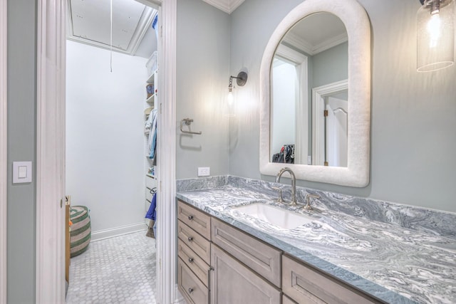 bathroom with a spacious closet, vanity, and crown molding