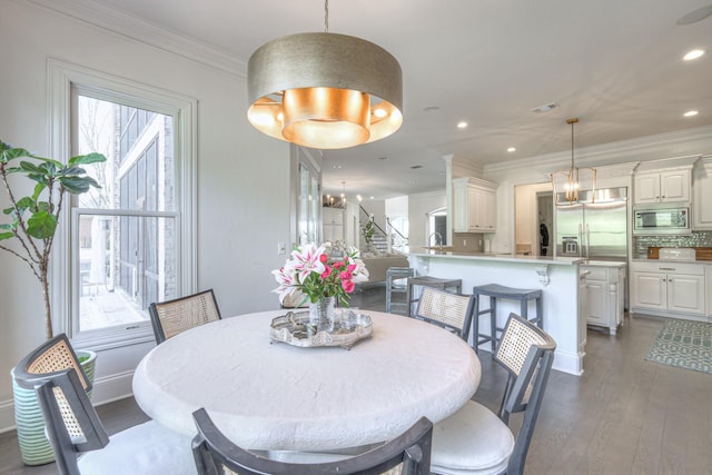 dining area with ornamental molding, a chandelier, plenty of natural light, and dark wood-style flooring