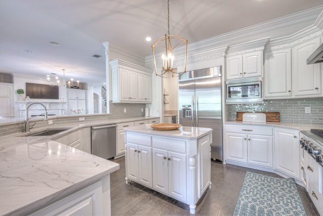 kitchen with white cabinets, a kitchen island, a sink, built in appliances, and a chandelier