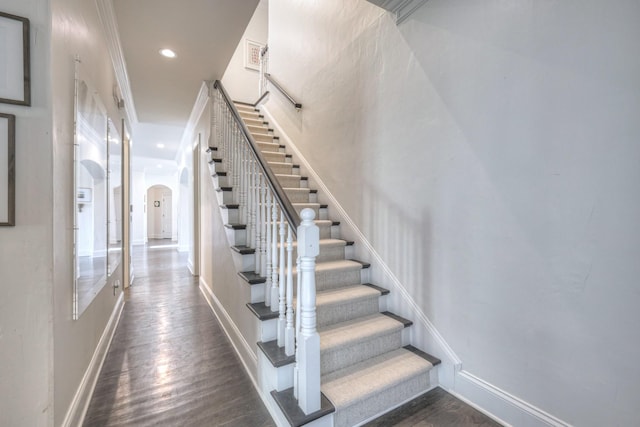 stairway with baseboards, arched walkways, wood finished floors, and recessed lighting