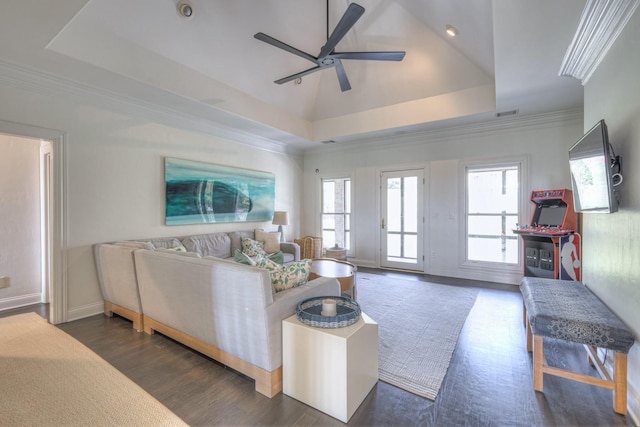 living room featuring plenty of natural light, ornamental molding, a raised ceiling, and dark wood-style flooring